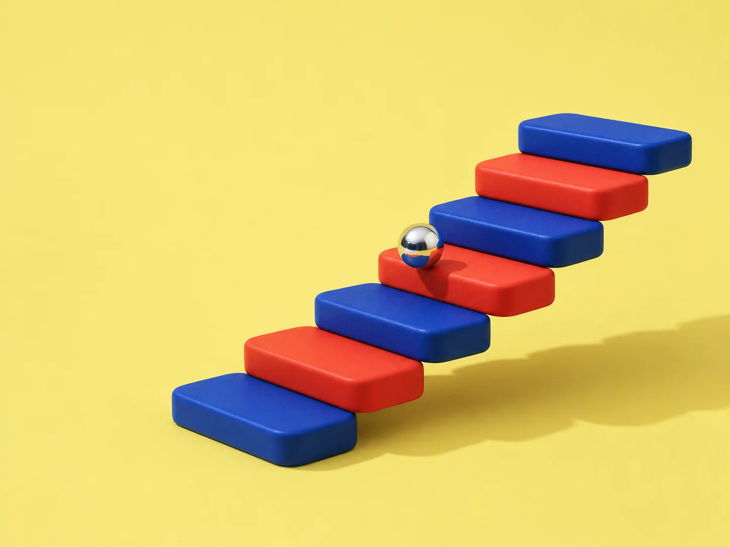 A small silver ball travelling up a floating red and blue staircase.
